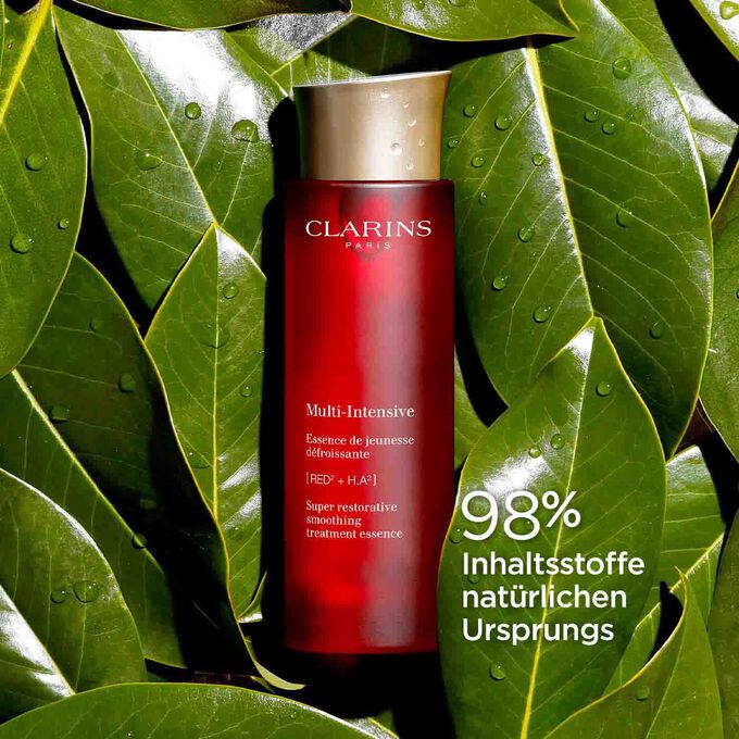 Packshot von Clarins Multi-Intensive Gesichtspflege-Essenz, umgeben von Haronga-Blättern, um den Anteil von 98 % natürlicher Inhaltsstoffe zu betonen.