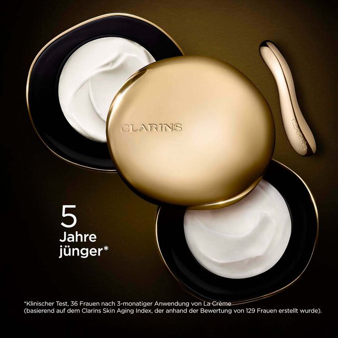 Clarins Precious La Crème Riche vor einem dunklen Hintergrund mit einem Text, der ihre Fähigkeit betont, die Haut 5 Jahre jünger wirken zu lassen