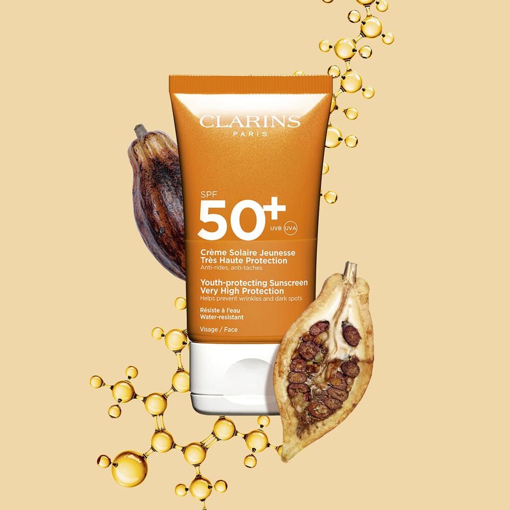 Packshot einer dunkelorangen Tube wasserfester Sonnencreme SPF 50 neben Kakaobohnen vor einem hellorangen Hintergrund