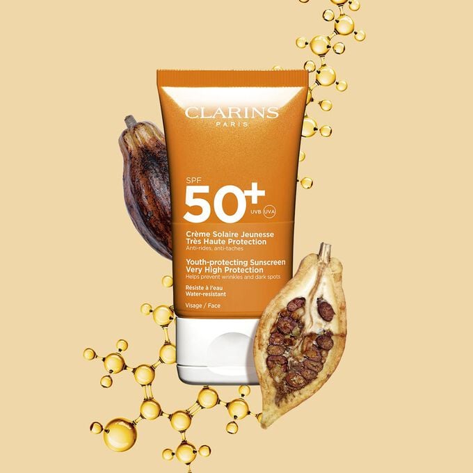 Packshot einer dunkelorangen Tube wasserfester Sonnencreme SPF 50 neben Kakaobohnen vor einem hellorangen Hintergrund