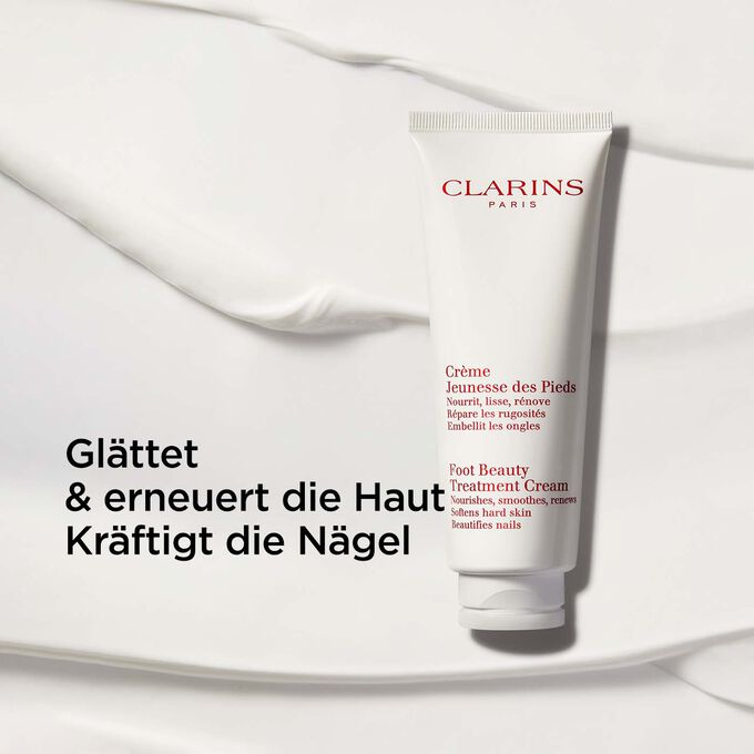 Packshot von Clarins Jeunesse des Pieds Fusscreme vor einem cremefarbenen Hintergrund mit Text, der ihre nährenden Eigenschaften betont.