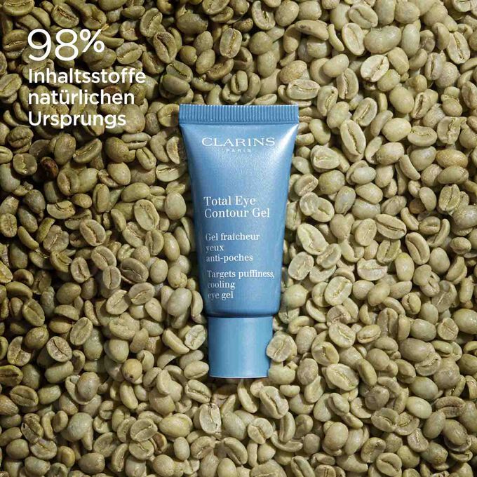 Tube mit Clarins Total Eye Contour Gel mit Kaffeebohnen, um den natürlichen Ursprung der Inhaltsstoffe des Produkts zu veranschaulichen.