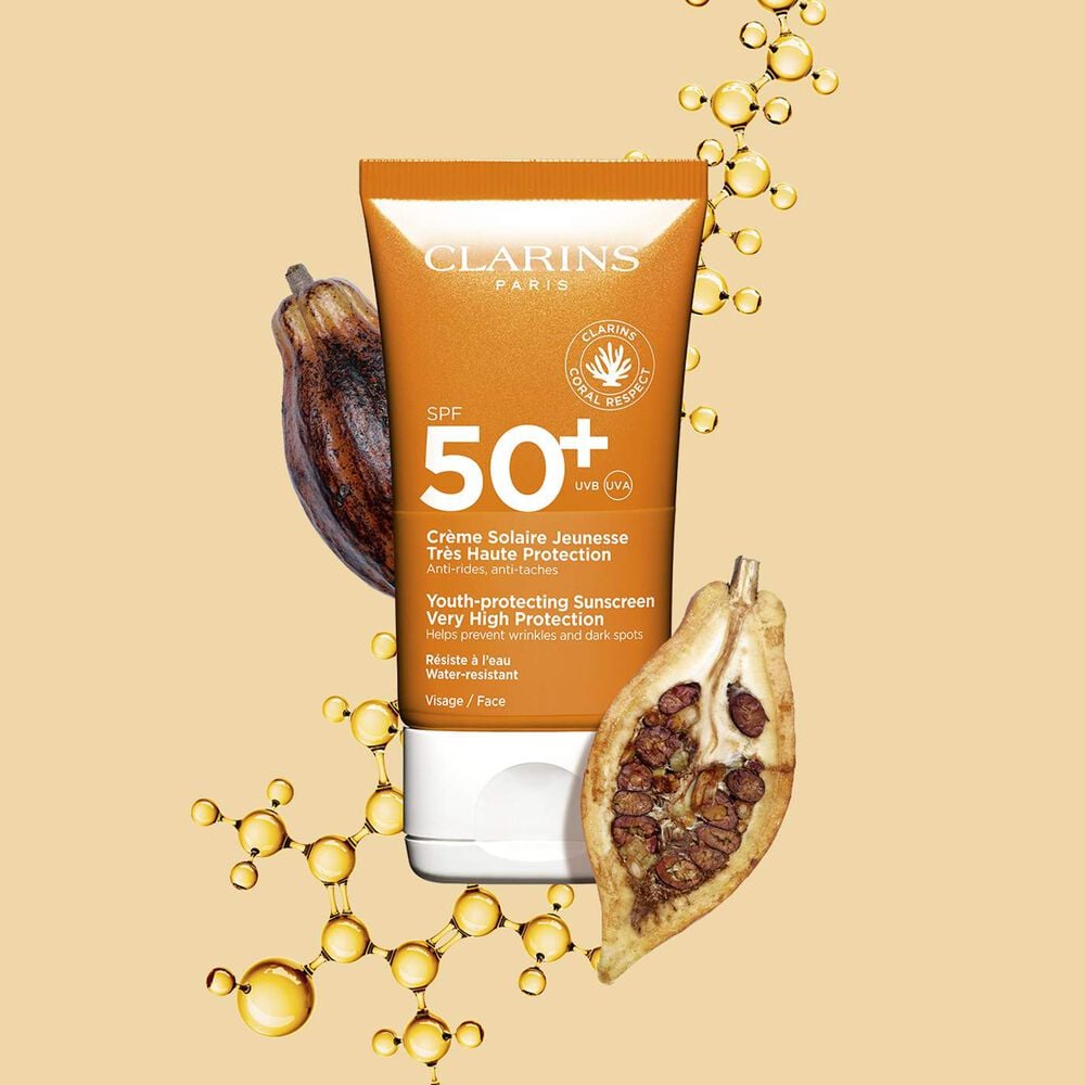 Packshot einer dunkelorangen Tube wasserfester Sonnencreme SPF 50 neben Kakaobohnen vor einem hellorangen Hintergrund