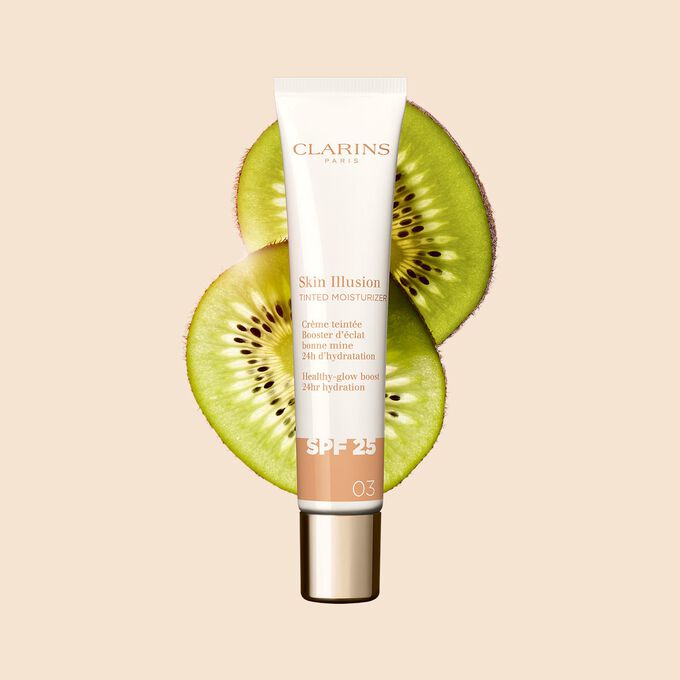 Plan produit du tube de 40 ml du perfecteur de teint Skin Illusion Tinted Moisturizer teinte 03, placé à côté de tranches de kiwi.