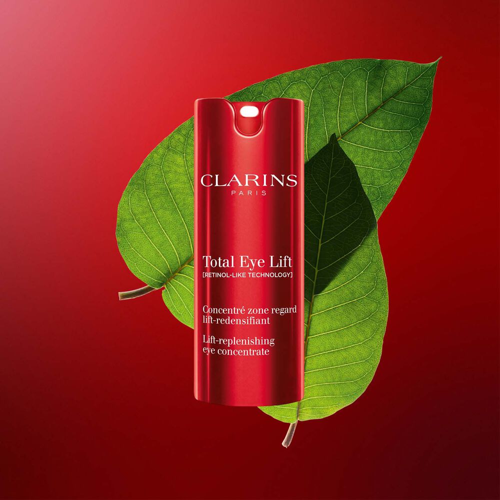 Plan produit de la crème yeux anti-âge Total Eye Lift de Clarins aux feuilles d’harungana sur fond rouge foncé.