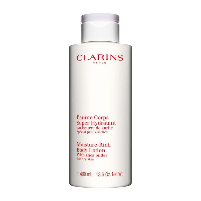 Plan produit d'un flacon de Baume Corps Super Hydratant Clarins avec des noix de karit&eacute; sur fond blanc.