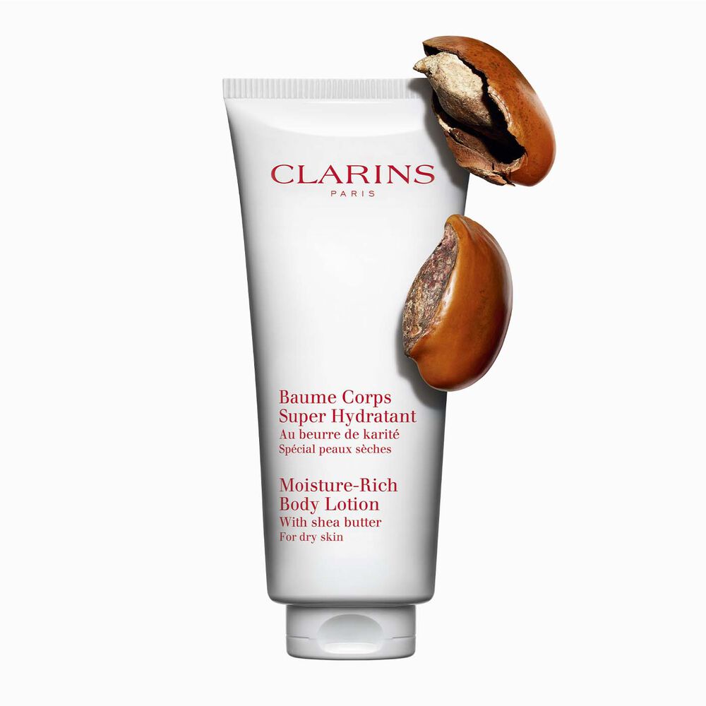 Plan produit d'un tube de Baume Corps Super Hydratant de Clarins avec des noix de karité sur fond blanc.