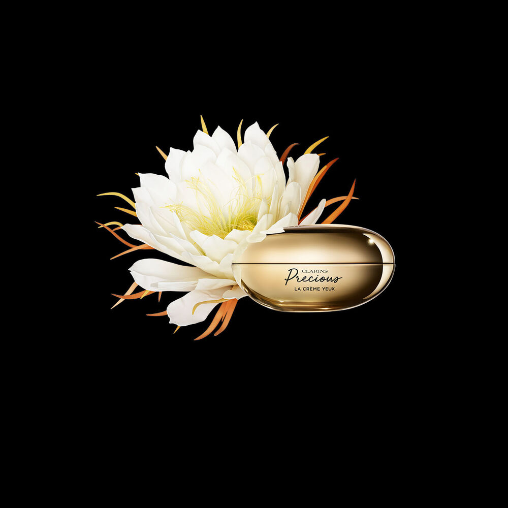 Packshot von Clarins Precious La Crème Yeux Augencreme mit einer Mondblume vor einem dunklen Hintergrund.
