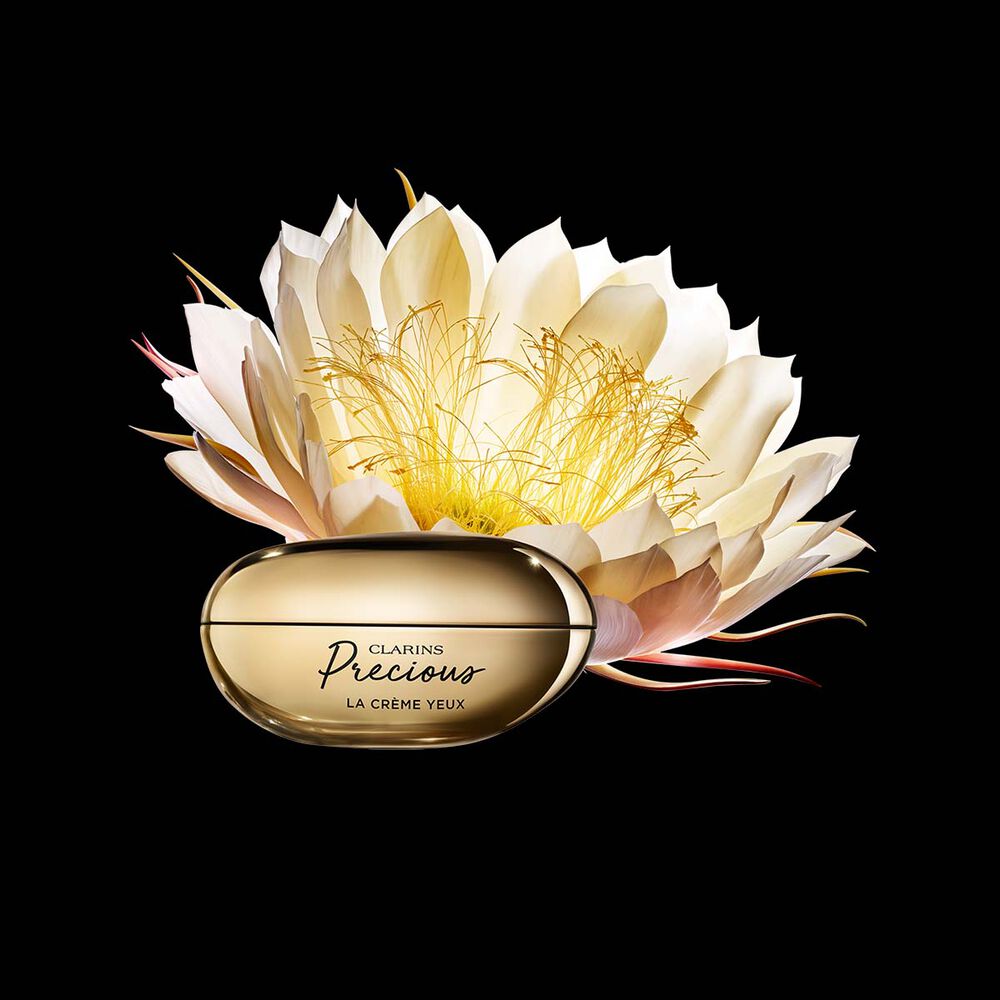 Packshot von Clarins Precious La Crème Yeux Augencreme mit einer Mondblume vor einem dunklen Hintergrund.