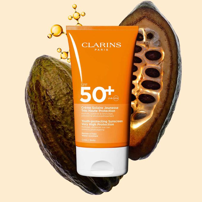Photo de la Crème Solaire Jeunesse Très Haute Protection SPF 50 Clarins pour le corps, parmi des molécules de collagène et des fèves de cacao.