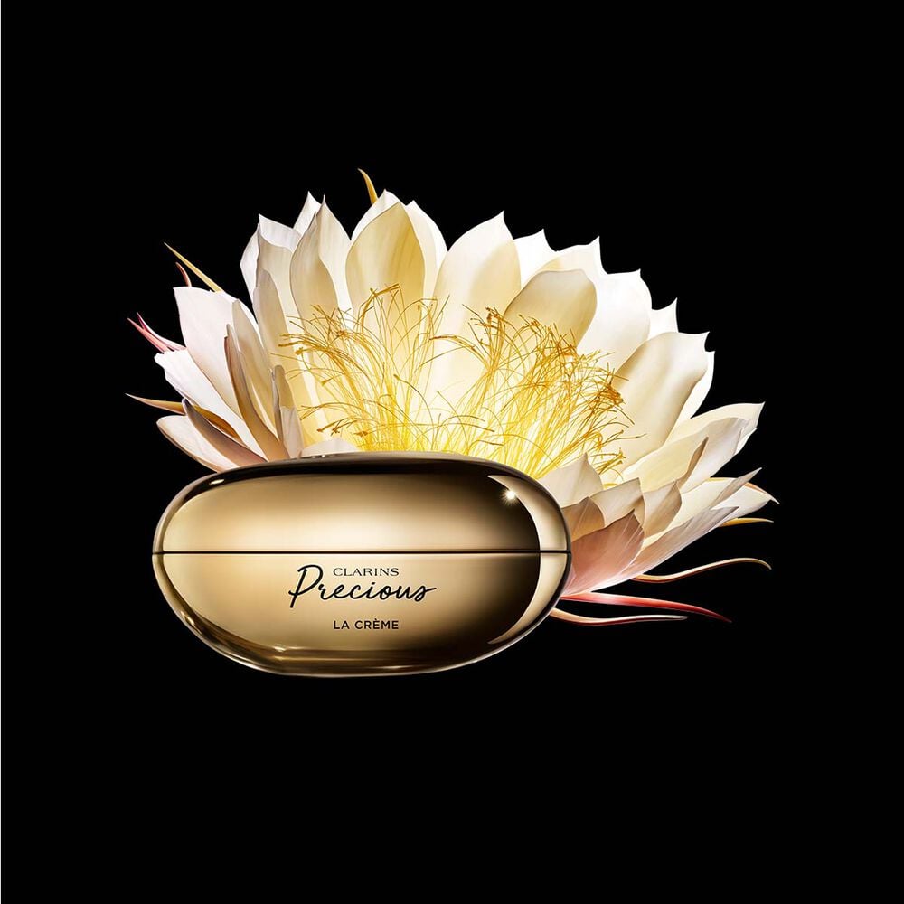 Packshot von Clarins Precious La Cr&egrave;me mit einer Mondblume vor dunklem Hintergrund.
