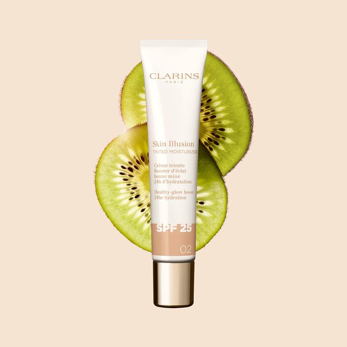 Plan produit du tube de 40&nbsp;ml du perfecteur de teint Skin Illusion Tinted Moisturizer teinte&nbsp;02, plac&eacute; &agrave; c&ocirc;t&eacute; de tranches de kiwi.