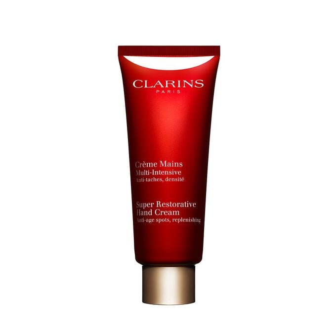 Packshot einer Tube Multi-Intensive Handcreme von Clarins mit ein paar Haronga-Bl&auml;ttern vor einem rosa Hintergrund.
