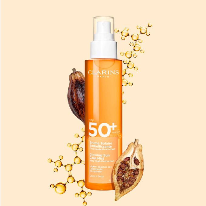 Plan produit de la Brume Solaire Embellissante SPF 50+ Clarins, un spray invisible, devant une molécule de collagène et des fèves de cacao.