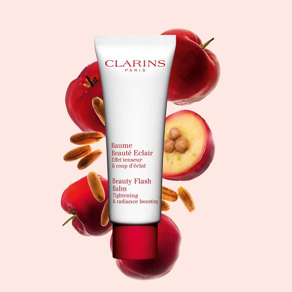 Plan produit d'un tube de Baume Beauté Éclair Clarins avec des baies d'acérola sur fond pêche.