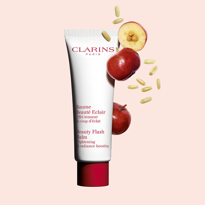 Plan produit d'un tube de Baume Beauté Éclair Clarins avec des baies d'acérola sur fond pêche.