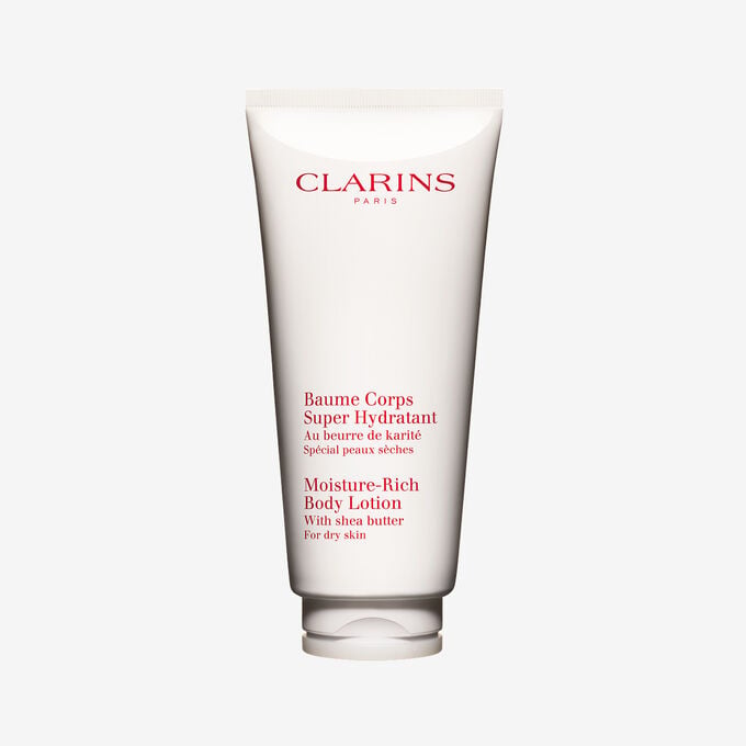 Packshot einer Tube Clarins Baume Corps Super Hydratant mit ein paar Shean&uuml;ssen vor einem weissen Hintergrund.