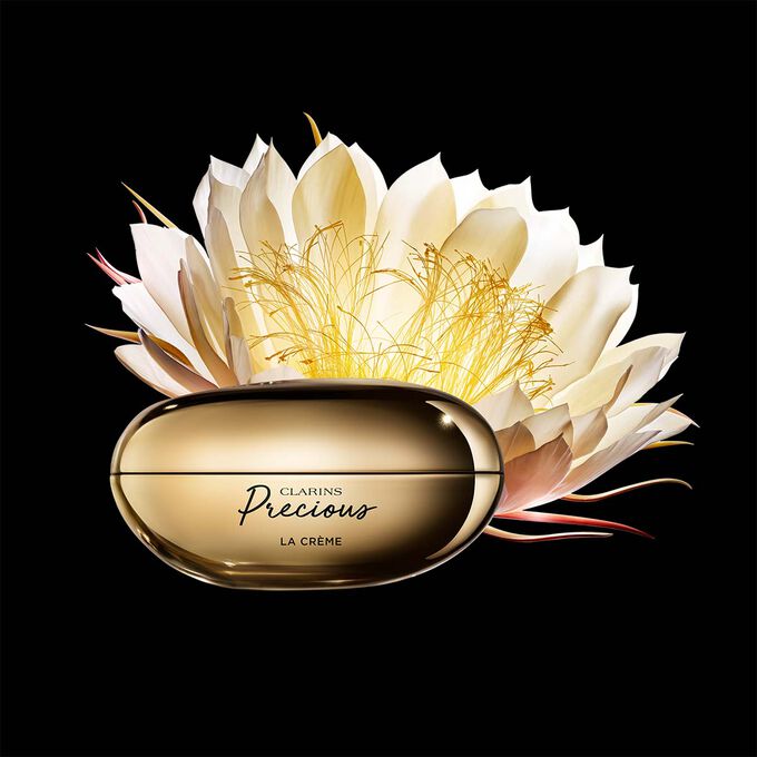 Packshot von Clarins Precious La Crème mit einer Mondblume vor dunklem Hintergrund.