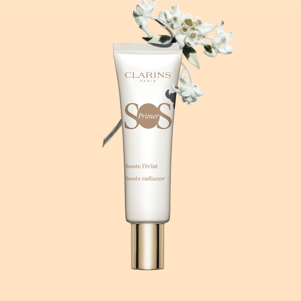 Packshot einer Tube SOS Primer White von Clarins mit Edelweissblüten, um den Glow und die Leuchtkraft der Haut zu verstärken.