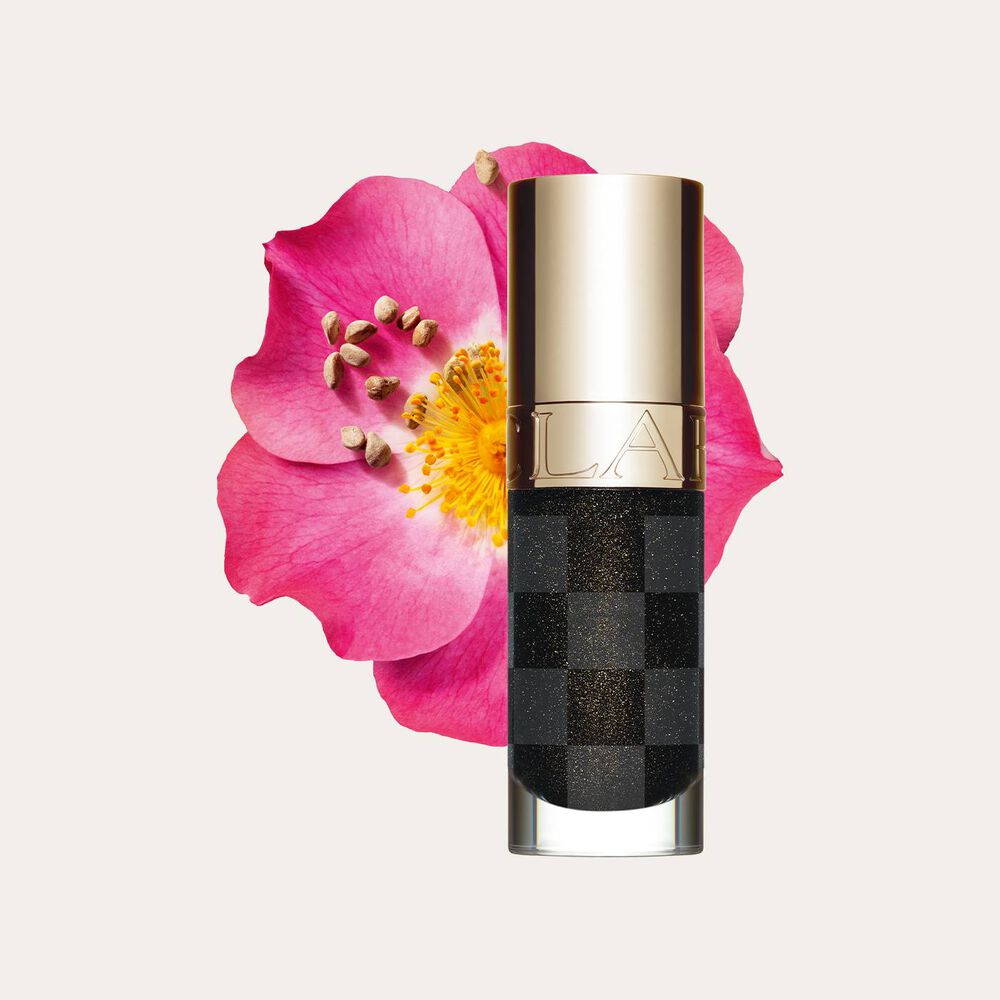 Plan produit de la nouvelle huile lèvres noire Clarins près d'un rosier rouillé