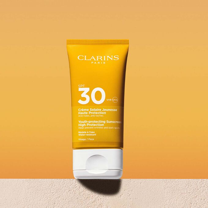Plan produit d'un tube de cr&egrave;me solaire visage SPF30 accompagn&eacute; d'un message annon&ccedil;ant que Clarins s'engage en faveur de la protection de l'environnement