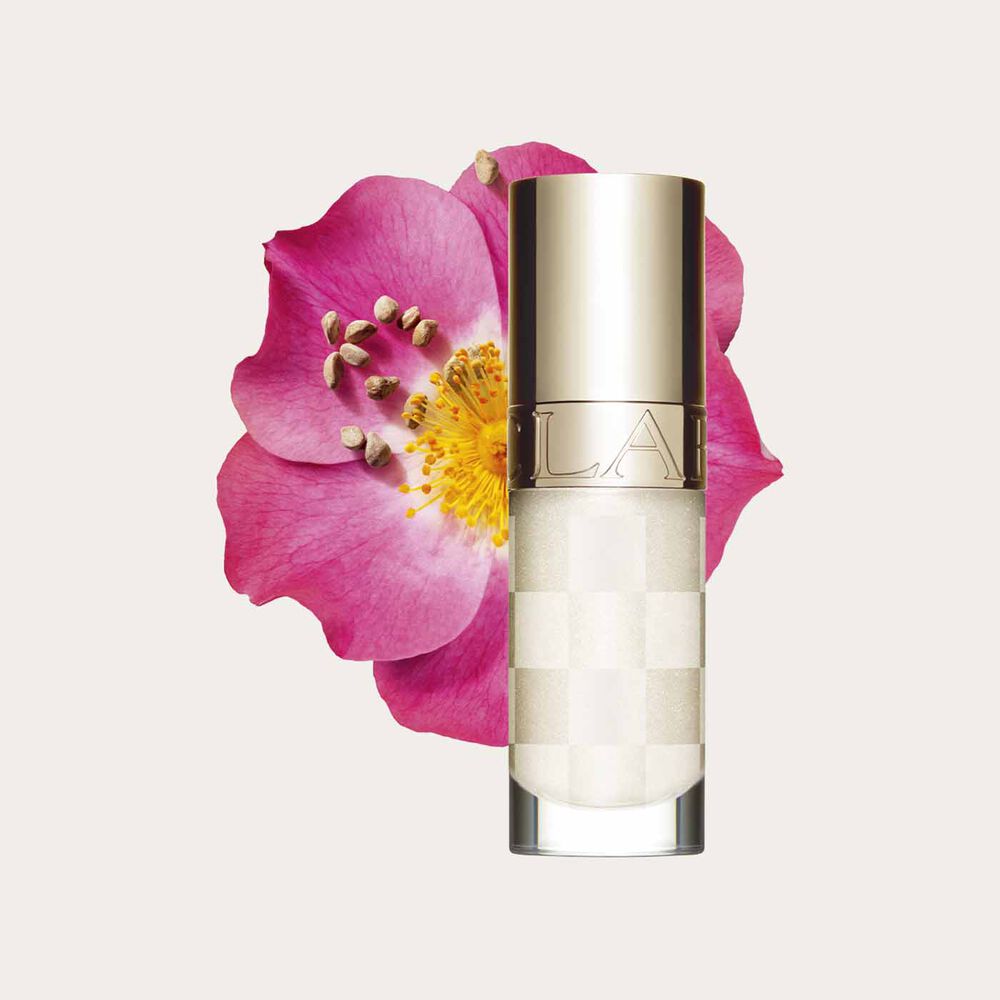Plan produit de la nouvelle huile lèvres blanche Clarins près d’un rosier rouillé