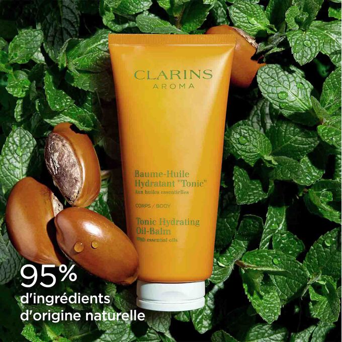 Baume-Huile Hydratant "Tonic" entouré de feuilles de menthe et de graines de karité pour l'origine naturelle des ingrédients