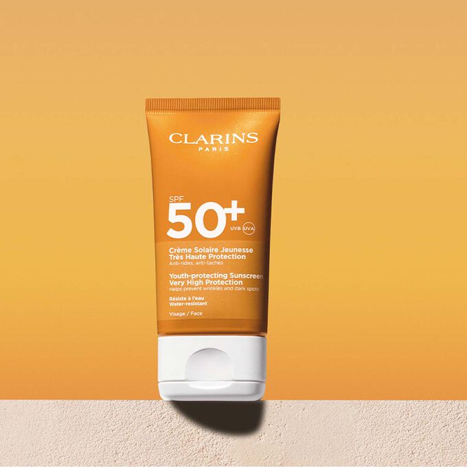 Plan produit d'un tube de cr&egrave;me solaire visage SPF50 accompagn&eacute; d'un message annon&ccedil;ant que Clarins s'engage en faveur de la protection de l'environnement
