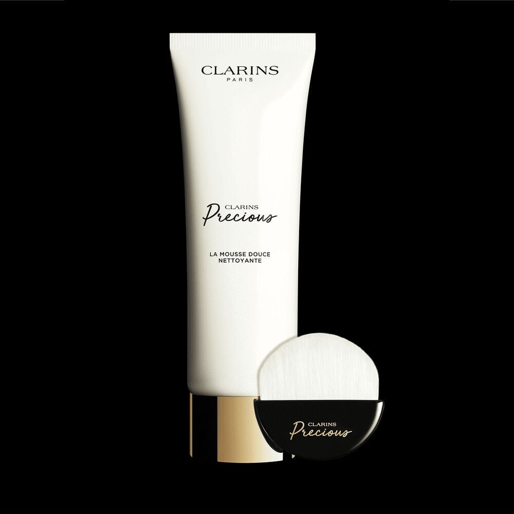 Plan produit du tube de nettoyant moussant et du pinceau nettoyant visage d&eacute;di&eacute;, &agrave; c&ocirc;t&eacute; d'une fleur de lotus brillante