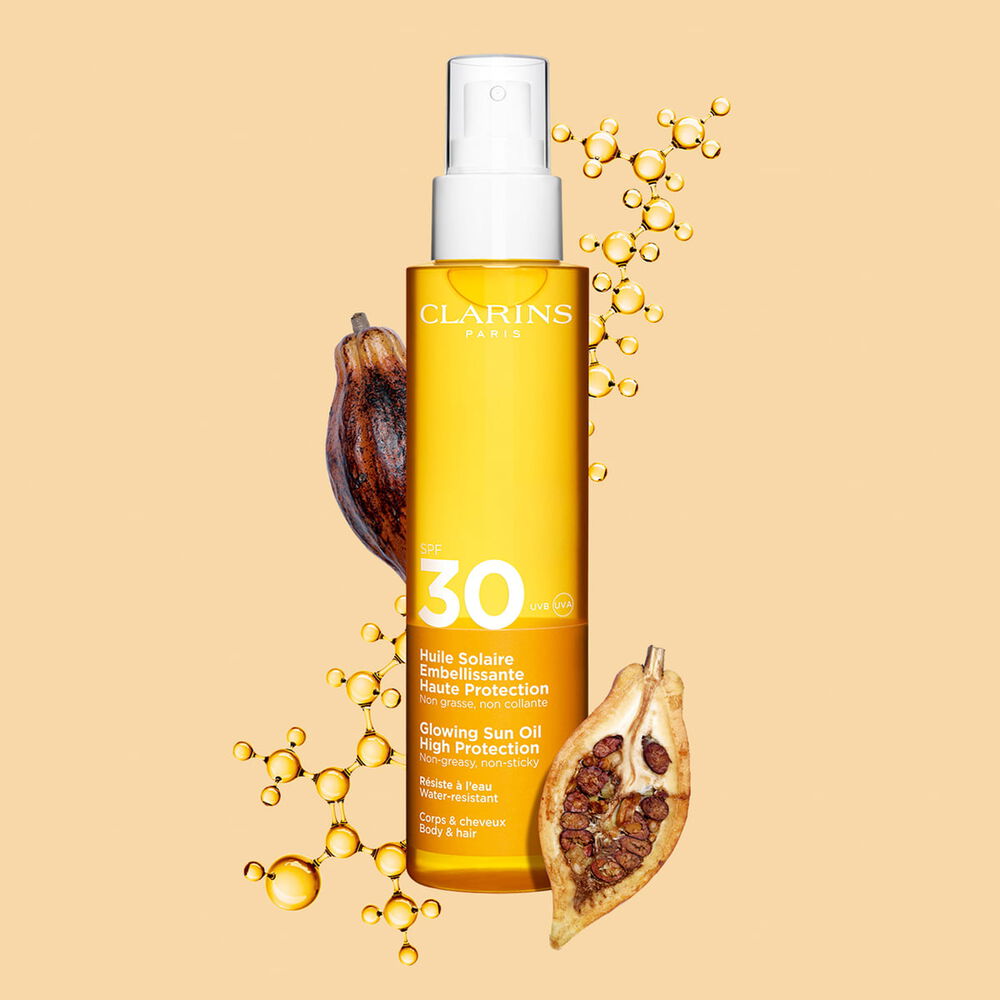 Plan produit de l'huile corps et cheveux SPF30 en spray orange &agrave; c&ocirc;t&eacute; de f&egrave;ves de cacao sur fond orange clair