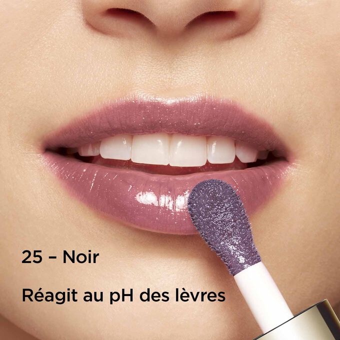 Gros plan sur des lèvres souriantes pour montrer la texture et la couleur de l’huile lèvres noire sur la carnation, qui réagit au pH des lèvres