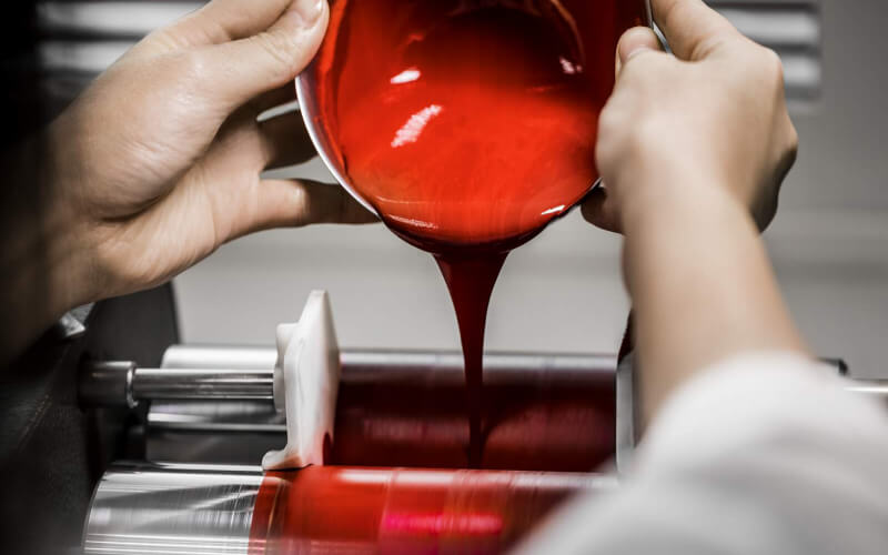 Ein Techniker giesst eine cremige Masse von rotem Make-up in eine Maschine