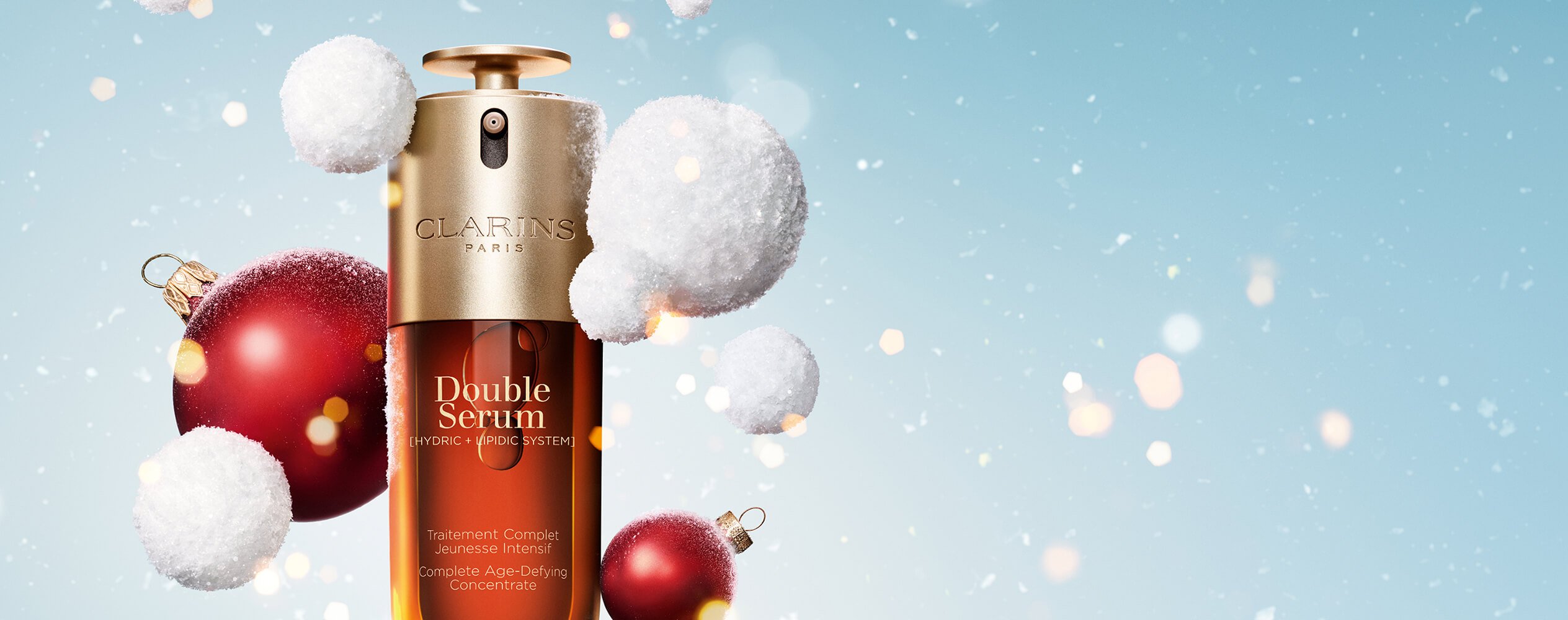 Double Serum auf weihnachtlichem Hintergrund mit Schnee, Schneebällen und roten Christbaumkugeln.